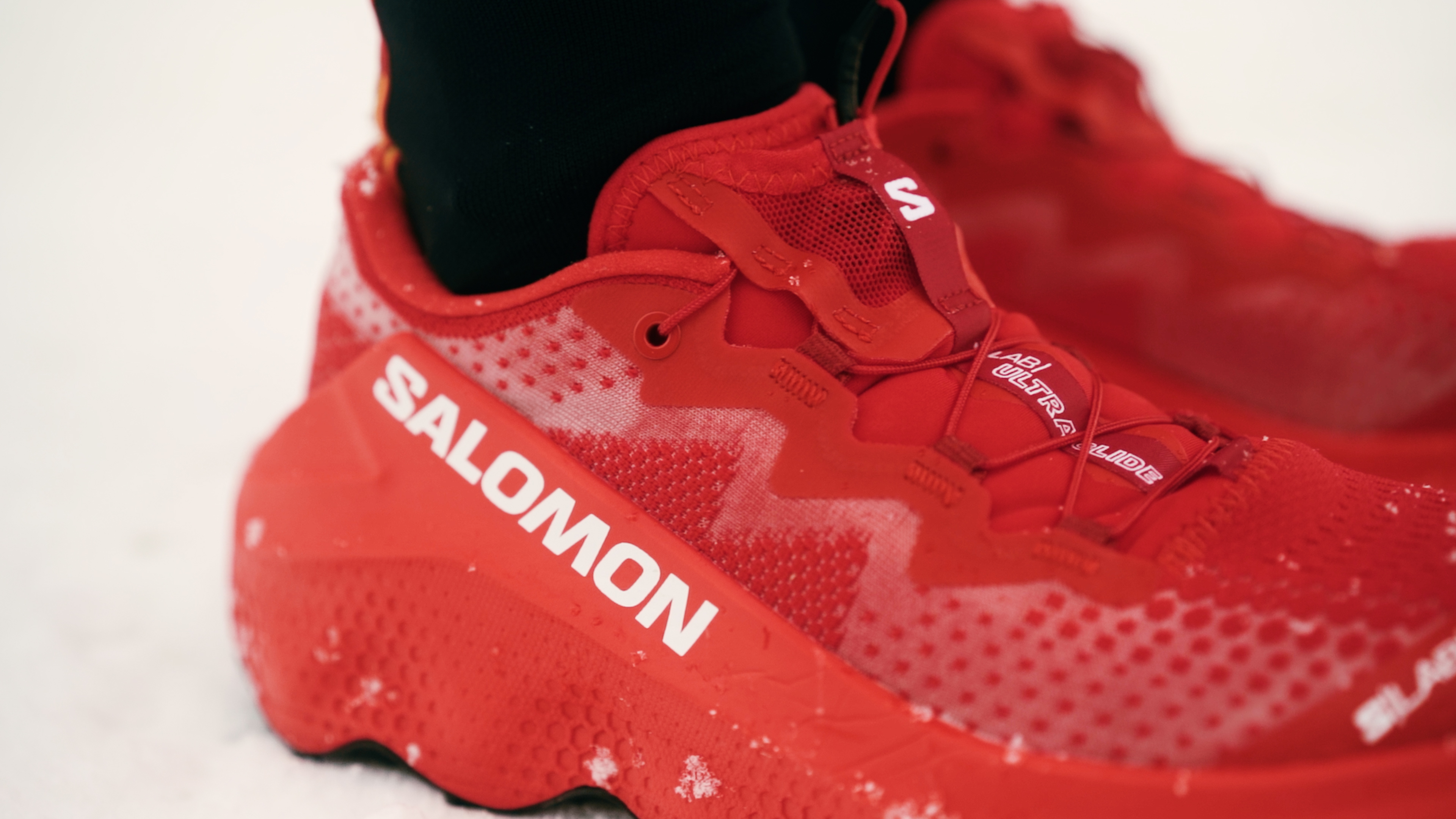 Close-up of red Salomon trail running shoe in the snow