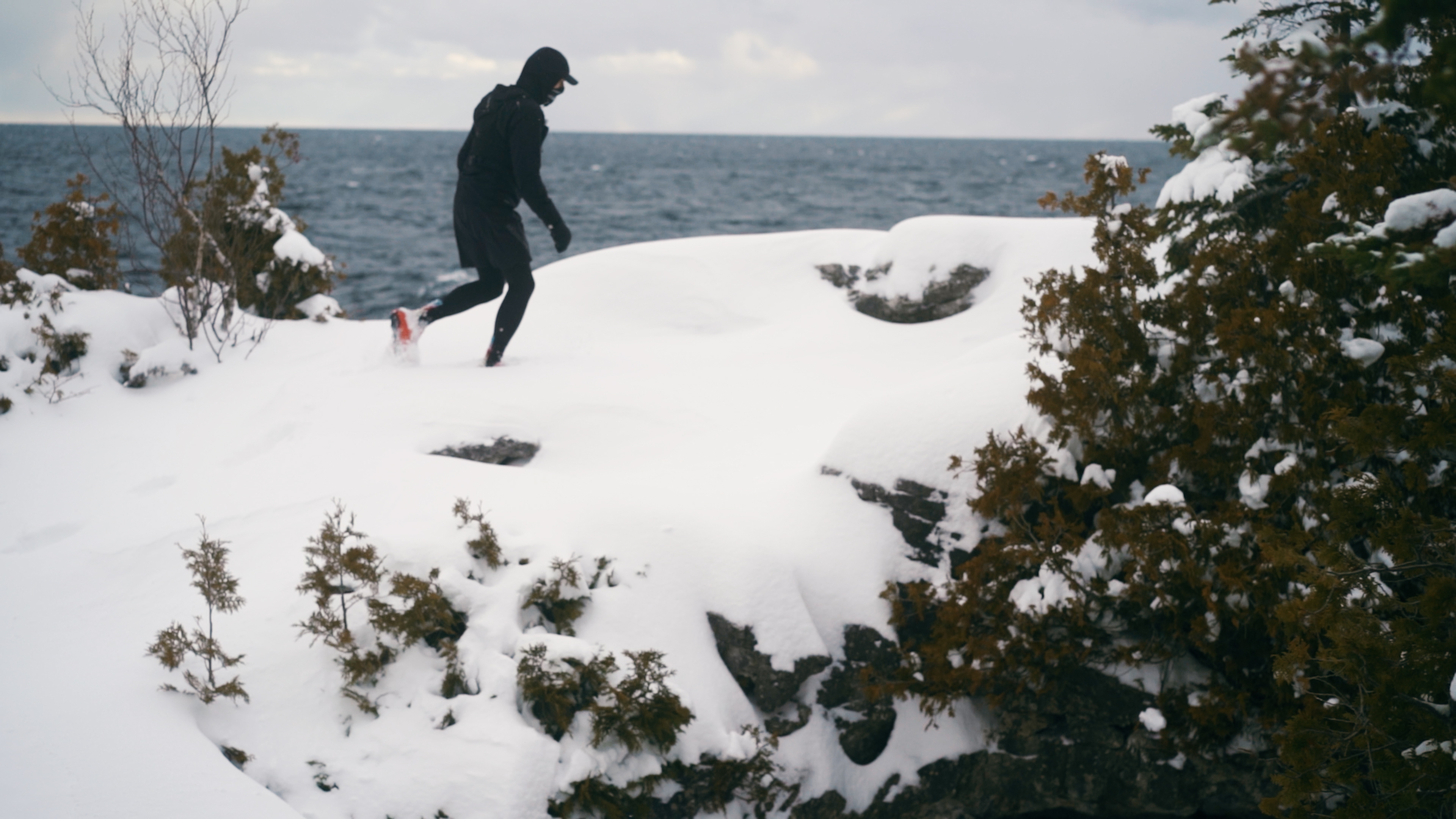Solo runner on a snowy cliff edge overlooking the lake